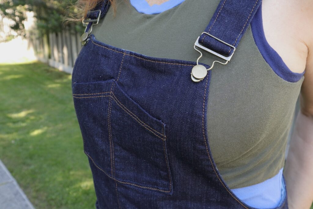 Close up of front bib pocket on denim overalls.