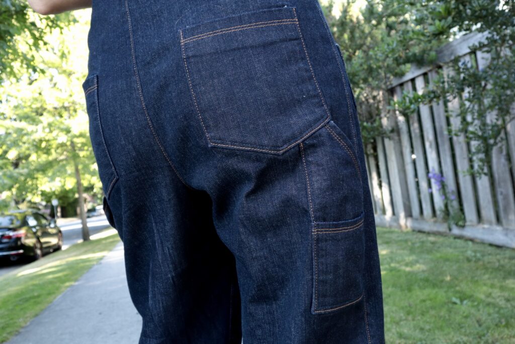 Close up of back and side pockets of denim overalls