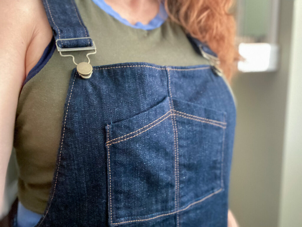 Close up of the pocket on the bib front of some denim overalls.