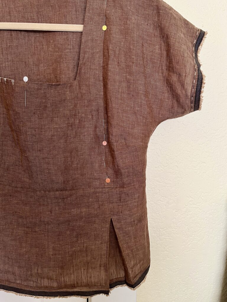 Close up of brown linen top with several pins on bodice