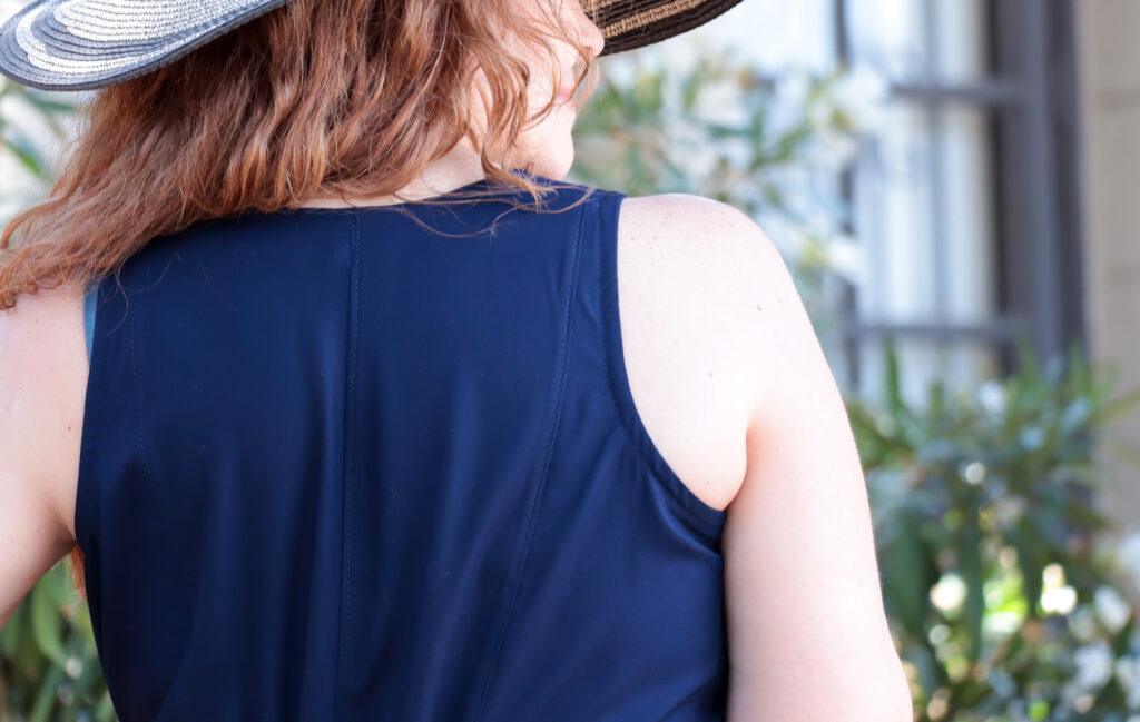 Detail of upper back of navy blue women's jumpsuit worn by a red-haired woman.