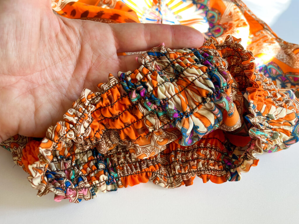 Detail of shirred waistband on an orange printed sleeveless top