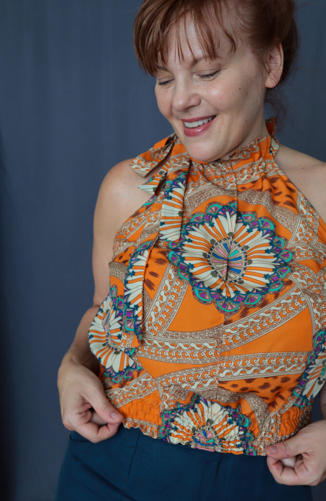 Close up of red-haired woman wearing an orange printed sleeveless top