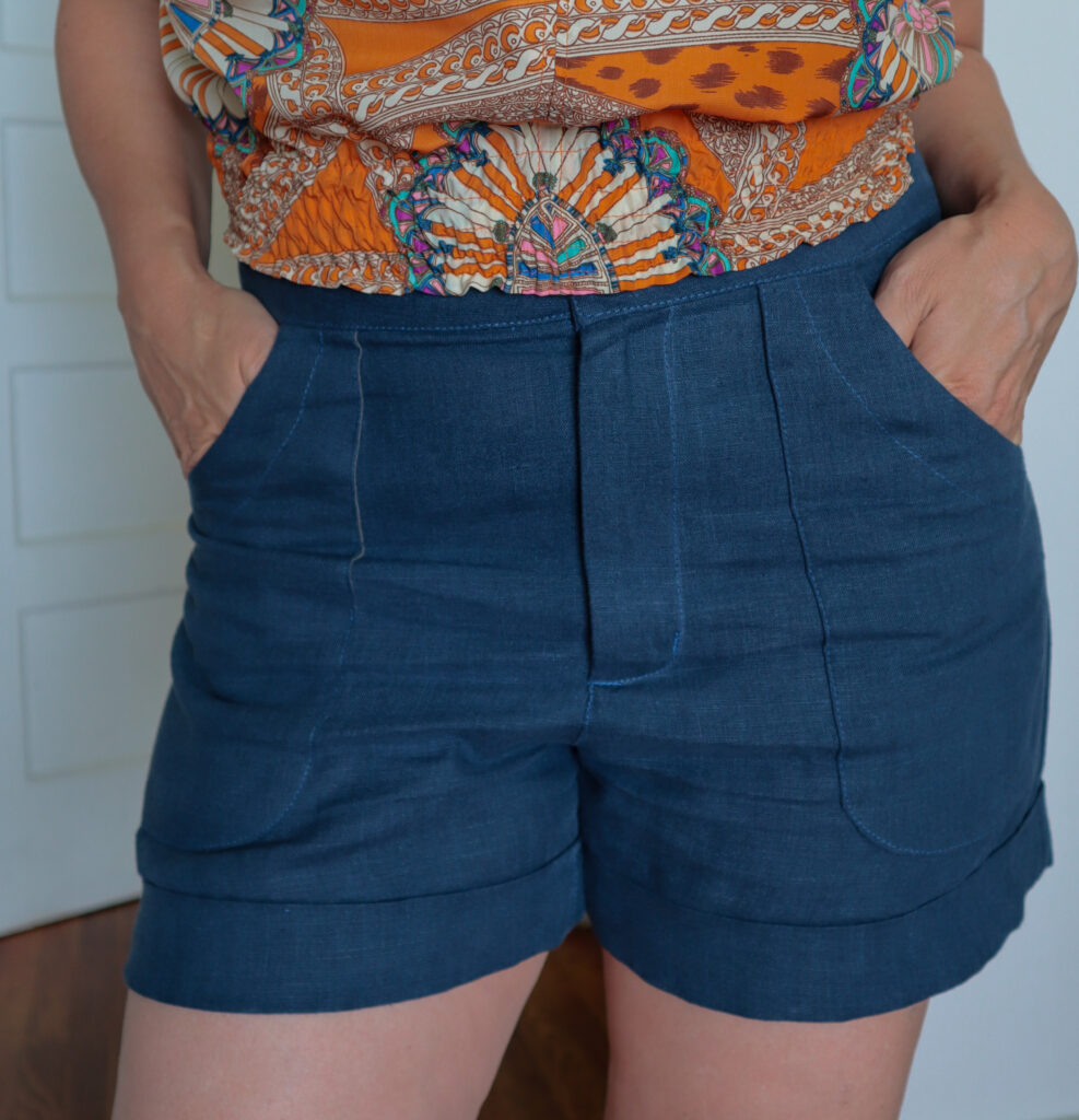 Detail woman wearing blue linen shorts with hands in front pockets
